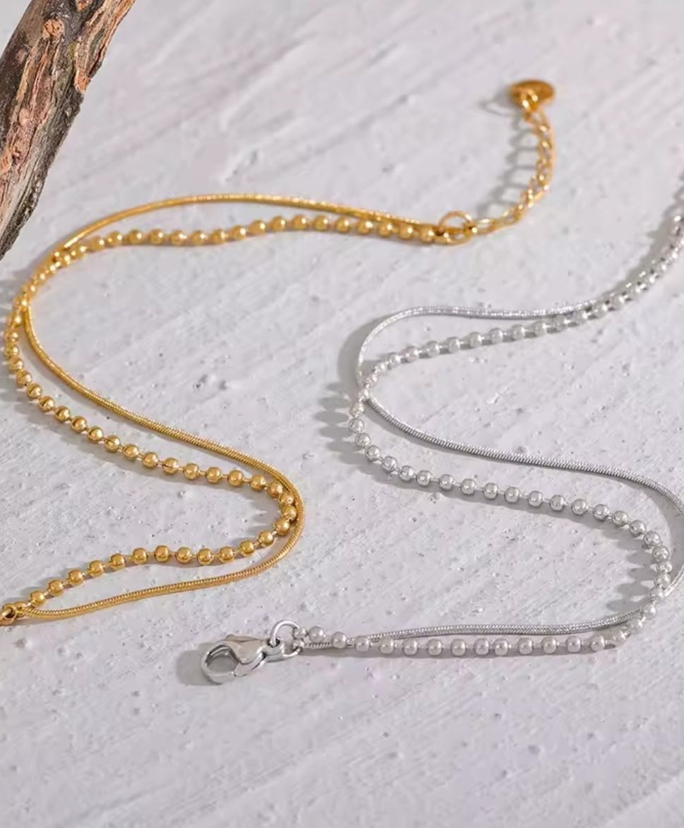 Bracelet Duo Perlé: Double chaîne dorée ornée de perles fines pour un style féminin, chic et tendance, parfait au quotidien ou en occasion spéciale. 